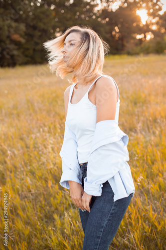 Young blonde woman is walking outdoors at evening