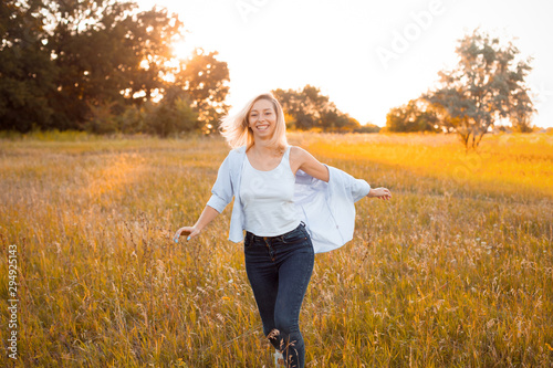 Happy young woman walking outdoors at sunset and laghing photo
