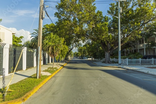 View of one of streets of Key West. Old houses and big green trees on blue sky background. Key West. Florida. USA. 