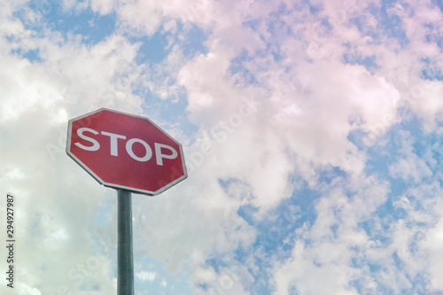 Road sign STOP with light cloudy sky in background.
