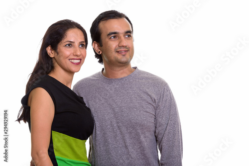 Studio shot of happy Persian couple smiling and looking at dista