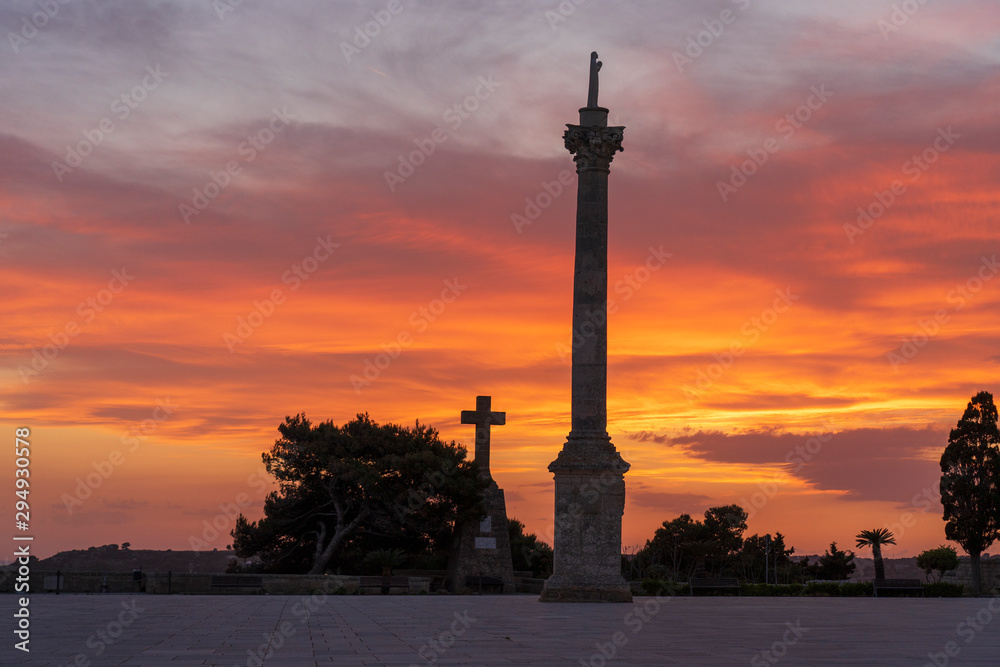 Fototapeta premium Sunset at Santa Maria di Leuca. Santa Maria di Leuca, Colonna Corinzia - Salento, Lecce, Apulia, Italy . Religious symbol, crucifix, cross - Immagine
