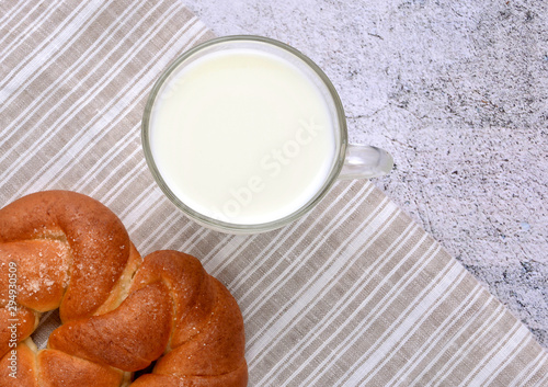 Glass of milk and sweet pretzel on a striped serviette. Delicious snack. Top view. Rustic. Space for a text.