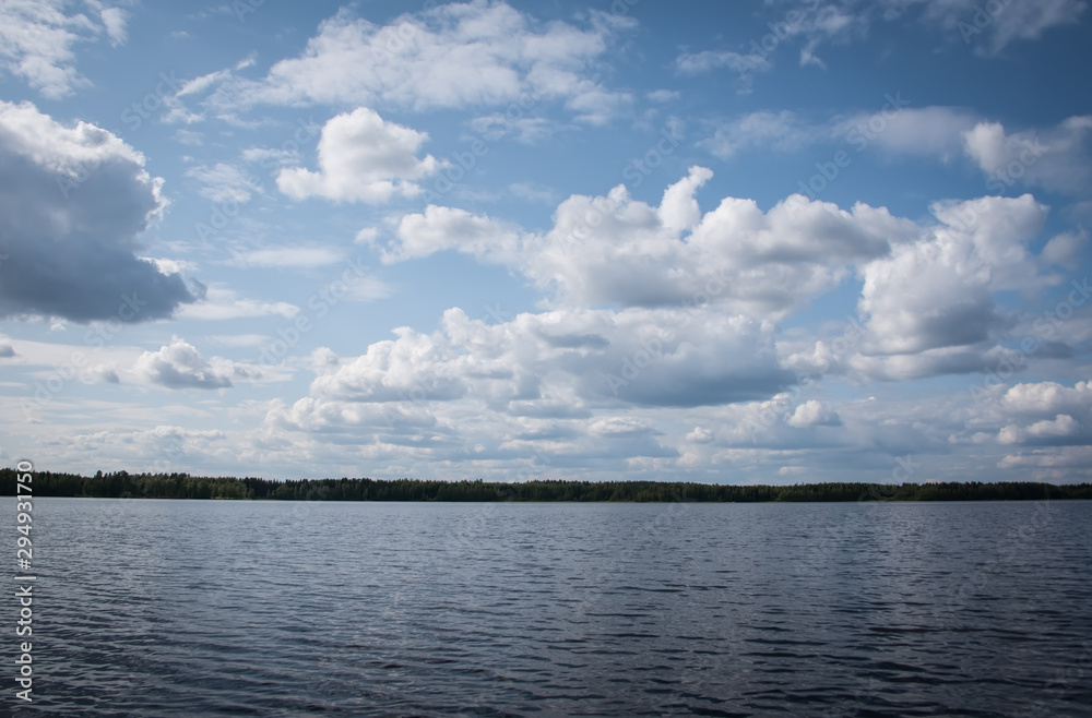 Summer view of the lake Hallanlahti with clouds on blue sky .