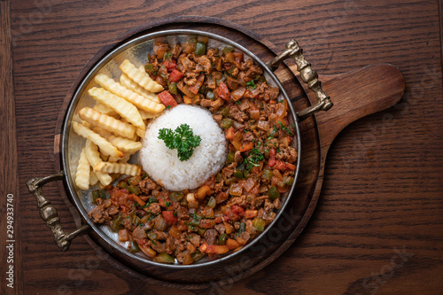 Turkish food lamb meat saute, sac kavurma with rice and french fries isolated on wooden table photo