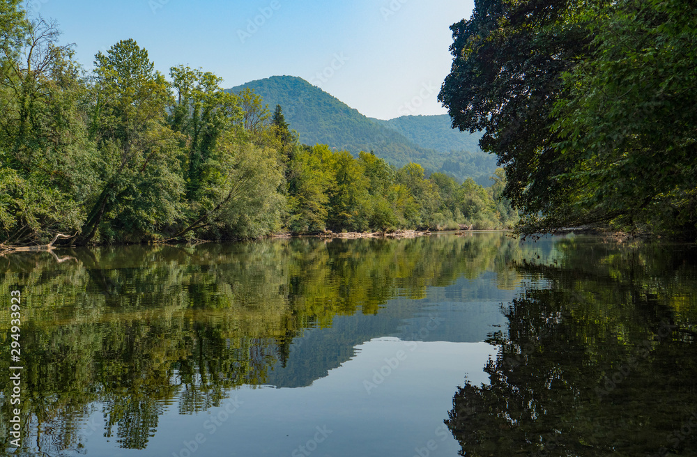 Picturesque view of the tranquil Kolpa river flowing through the lush forests.