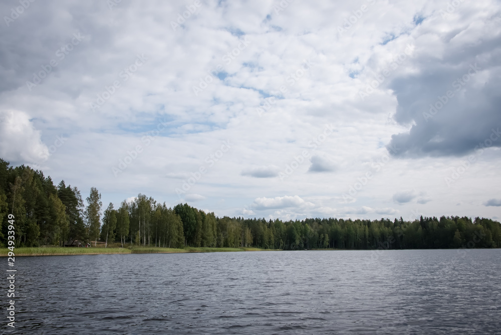Summer view of the lake Hallanlahti with reflection of clouds on the surface of the water . Finland .