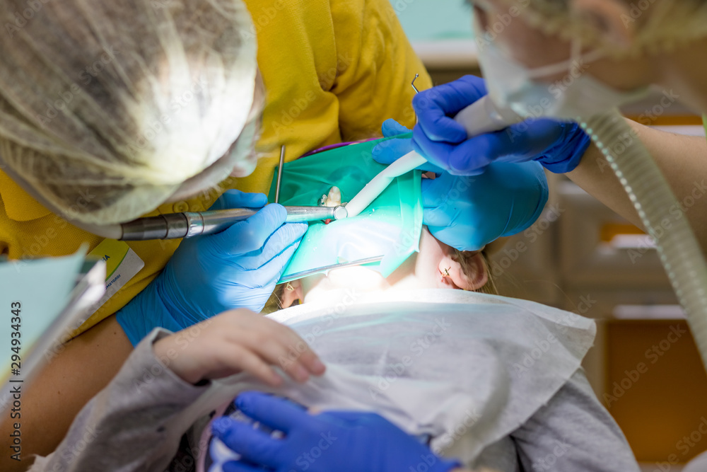 Dentist performing dental filling procedure to preteen girl in