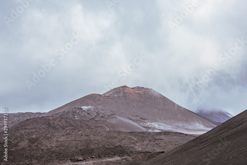 Volcanic landscape with frozen lava fields in cloudy weather on mountain peaks.