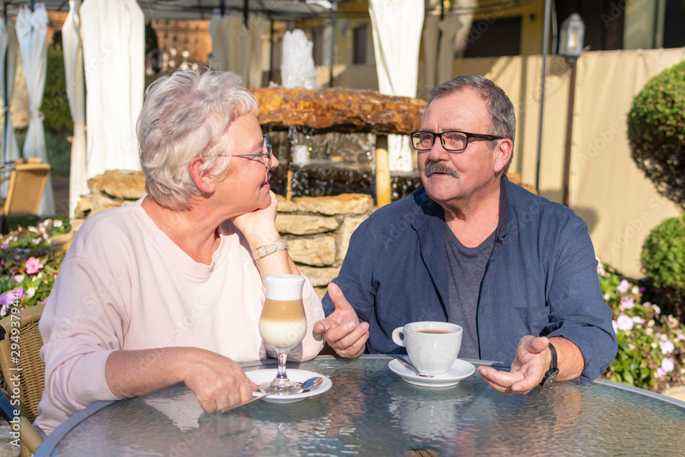Loving Senior Couple Enjoying coffee and Talking At Outdoor Cafe. Happy retirement concept Loving Senior Couple Enjoying coffee and Talking At Outdoor Cafe. Happy retirement concept