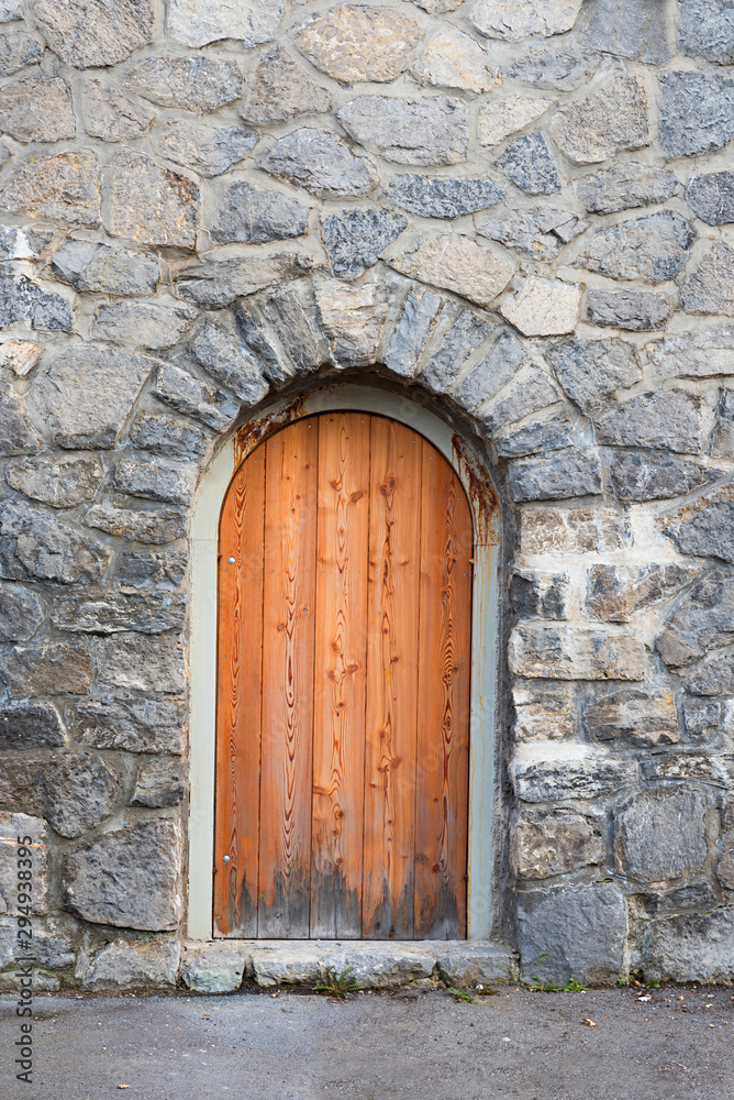 wall with grey natural stones and wooden arched door wall with grey natural stones and wooden arched door
