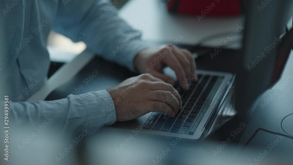 Man's well-groomed hands in a shirt type on a laptop keyboard. The sunbeam shines on the keys. The concept of working at the computer: a man quickly typing on the keyboard