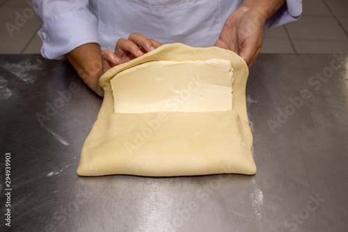 Chef hands making and folded raw puff pastry. Making puff pastry.   on a stainless steal table. First step, dough and the butter on the table.Close up. pastry chef. how to make.