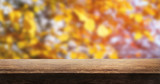 A wooden table top product display with a blurred background scene of tree foliage at sunset.