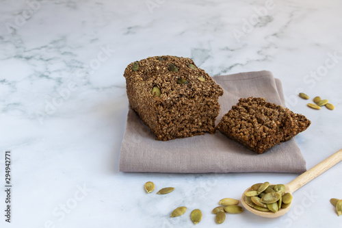 Gluten-free cereal bread with pumpkin seeds. Without flour, without yeast. Wooden spoon with pumpkin seeds. Horizontal orientation. Copy space.