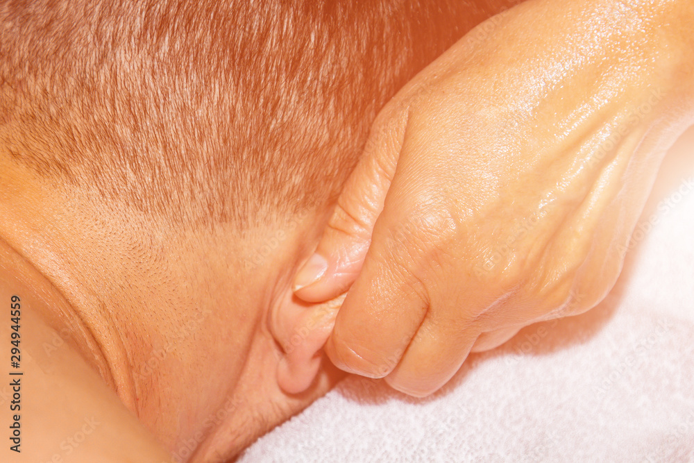 Fototapeta premium Female professional massage therapist makes therapeutic therapeutic massage of the ears with the hands of a male athlete. woman massages a man