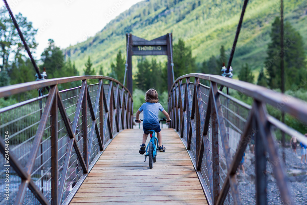 Rear view of boy riding mountain bike on bridge Rear view of boy riding mountain bike on bridge