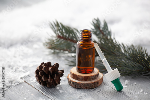 pine aroma oil extract natural with pipette in cosmetic bottles aromatherapy on winter snowy background
