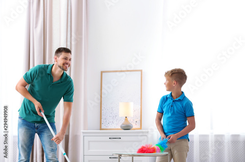 Dad and son cleaning living room together © New Africa