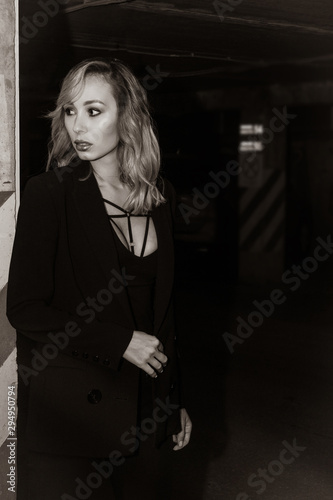 Noir film style woman in a black suit posing in an undergound car park.... © Demian