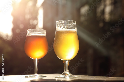 Glasses of cold tasty beer on wooden table outdoors