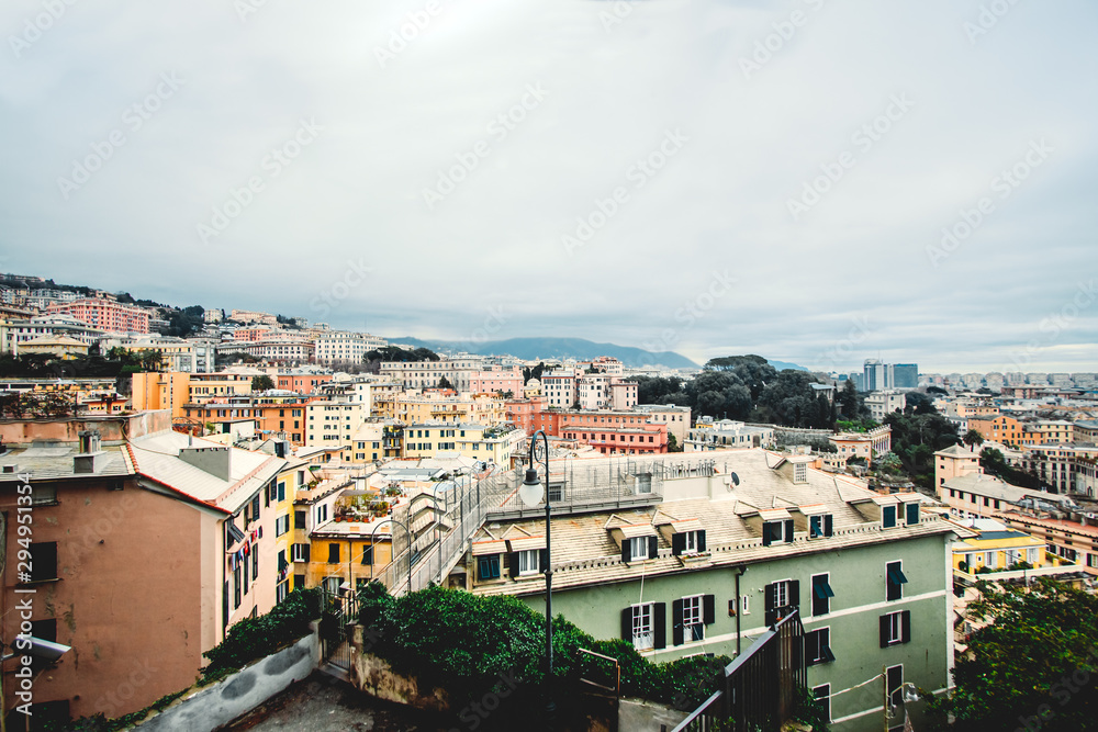 Many beautiful old italian houses painted in bright colors with mountains on the background.An amazing cityscape of some public housing in Genova built in the 60s over hills of the city in cloudy day,
