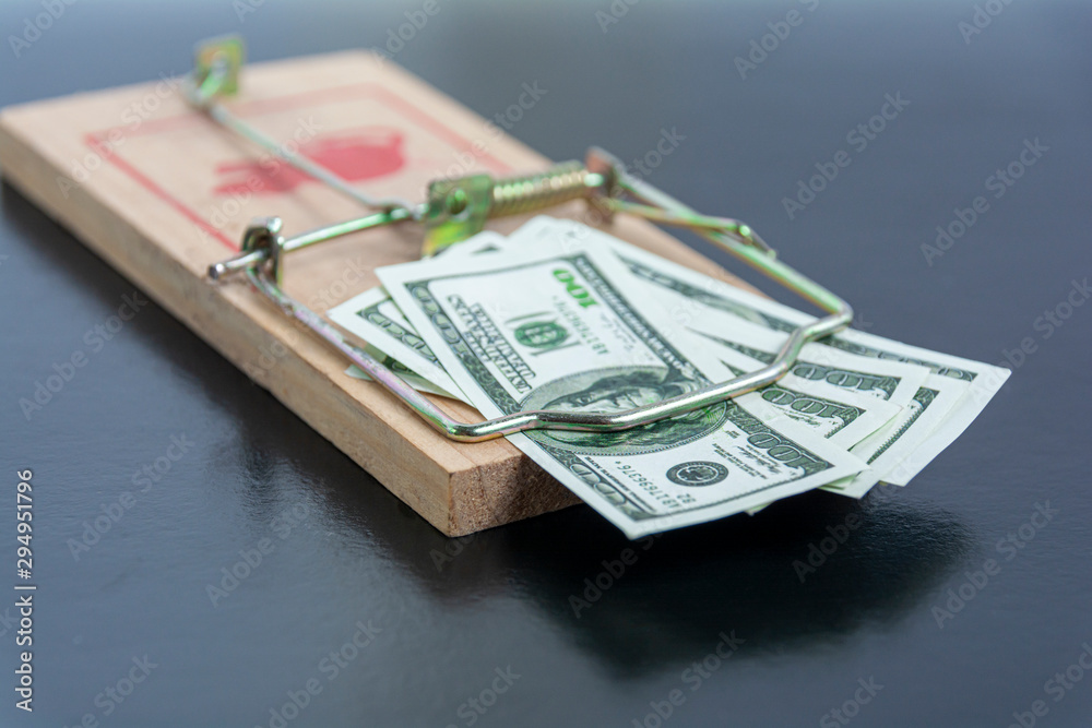 American dollar bills in a mousetrap close-up on a black background. Concept: financial trap, lending, debt. American dollar bills in a mousetrap close-up on a black background. Concept: financial trap, lending, debt.