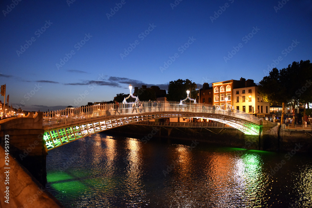Night view of famous illuminated Ha Penny Bridge in Dublin, Ireland, at sunset