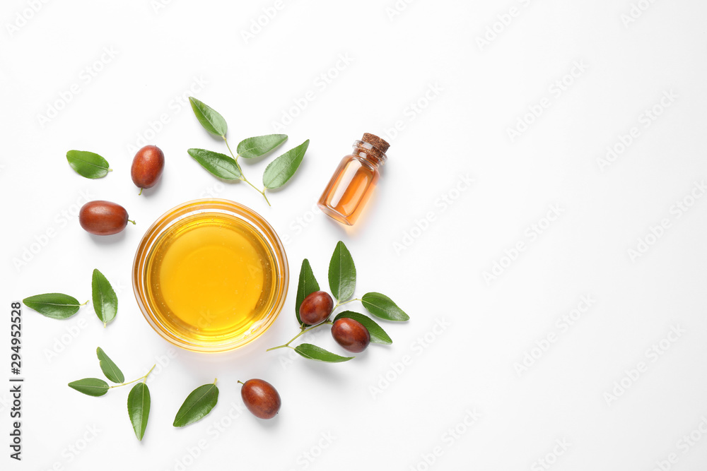 Bowl with jojoba oil and seeds on white background, top view