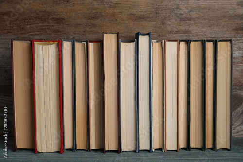 Stack of hardcover books on light blue table against wooden background