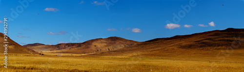 panorama view of vast grassland, landscape with mountains and blue sky