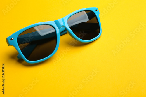 Stylish sunglasses on yellow background, space for text. Fashionable accessory