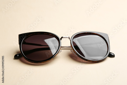 Stylish sunglasses on beige background. Fashionable accessory