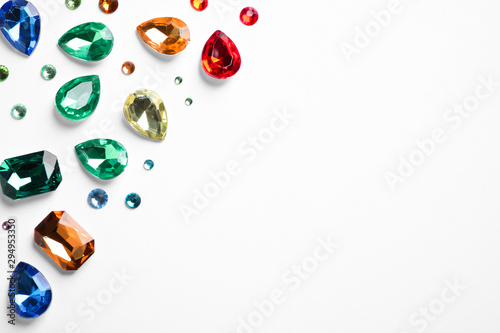 Different beautiful gemstones on white background, top view photo