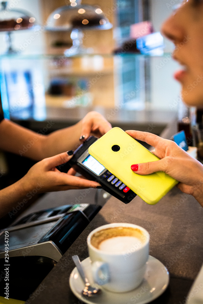 Close-up of customer paying cashless with smartphone in a cafe Close-up of customer paying cashless with smartphone in a cafe