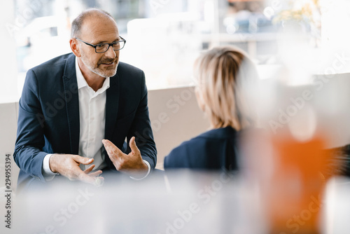 Businessman and woman having a meeting in a coffee shop, discussing work photo