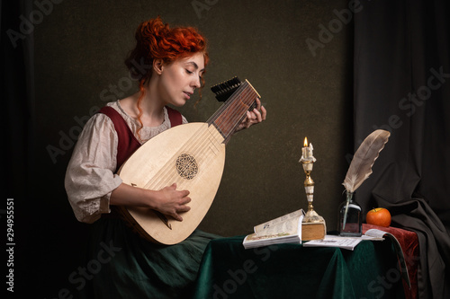 Photos Red-haired girl in a historical suit plays the lute