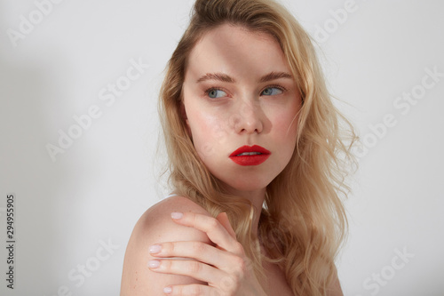 Portrait of young blond woman with red lips and shadow on her face
