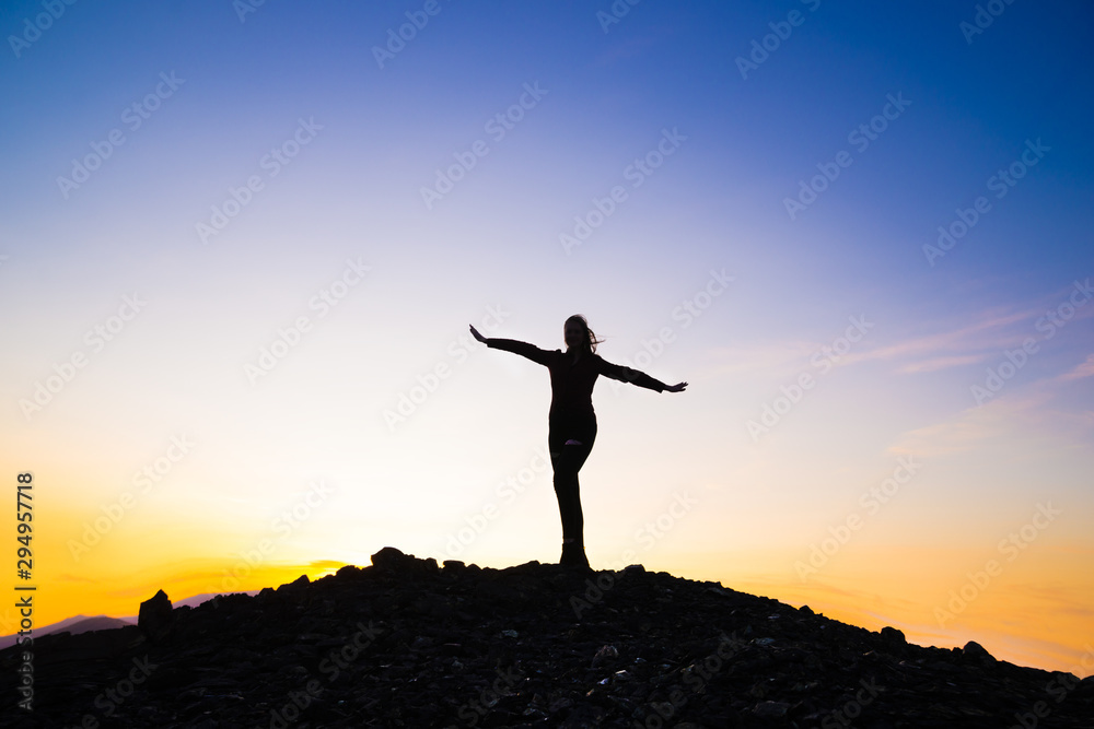 Silhouette of a happy young girl on top of a mountain holding up hands. against the sunset. Success, achievement concept. outdoors Silhouette of a happy young girl on top of a mountain holding up hands. against the sunset. Success, achievement concept. outdoors