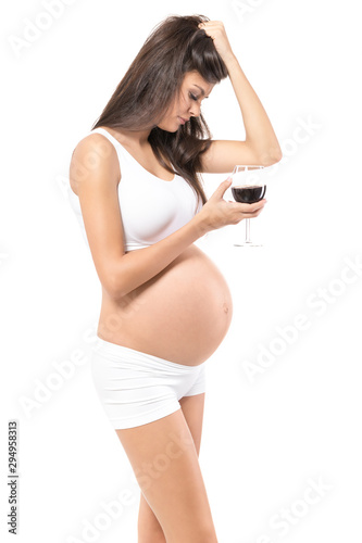 Pregnancy. Young, pregnant woman, on isolated white backgrou.nd holding glass of wine.