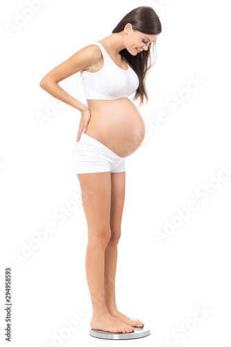 Pregnancy. Young, pregnant woman, on isolated white background checking weight.