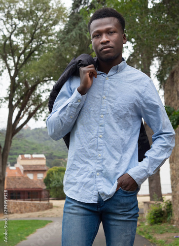 Hombre joven negro de Senegal con chaqueta en el hombro y camisa clara arrugada.