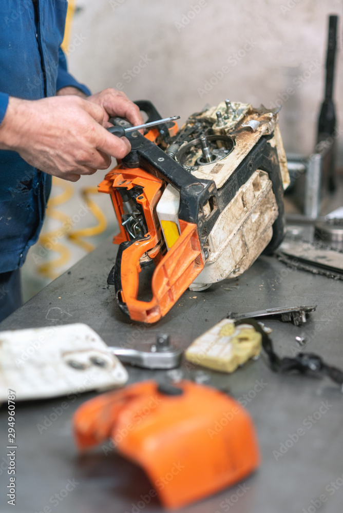 Mechanic repairing a chainsaw. Man repairing a chainsaw in workbench .