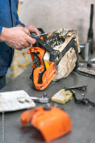 Mechanic repairing a chainsaw. Man repairing a chainsaw in workbench .