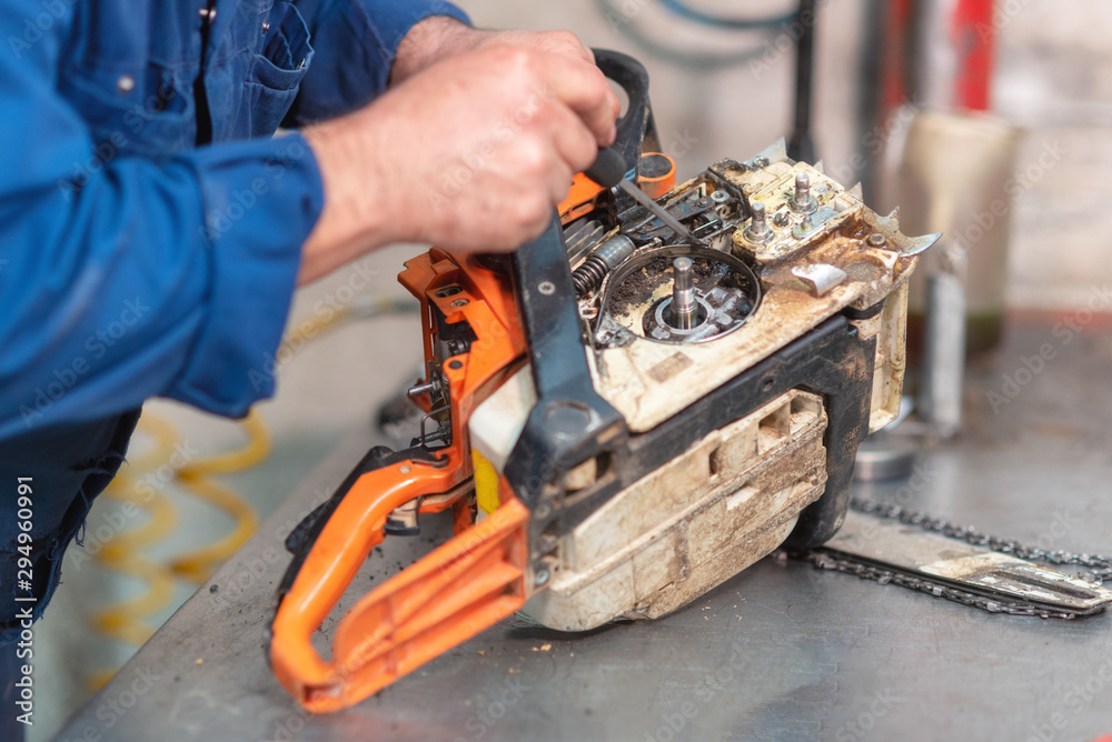 Mechanic repairing a chainsaw. Man repairing a chainsaw in workbench