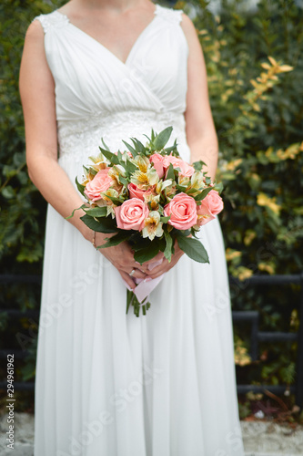 pregnant bride in a white dress holds a bouquet in her hands