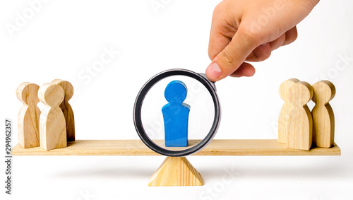 Cuadro en lienzo A magnifying glass looks at a leader stands on the scales between two groups of people