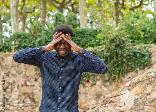 Hombre joven negro de Senegal con las manos en la cabeza y gesto de dolor