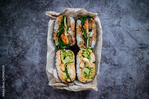 Take away sustainable packaging with curry onigirazu and tofu onigirazu on concrete background. Japanese food. Top view. photo