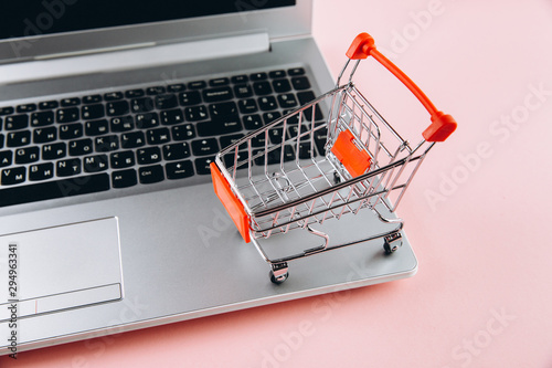 Black friday concept. Red trolley and laptop on pink background